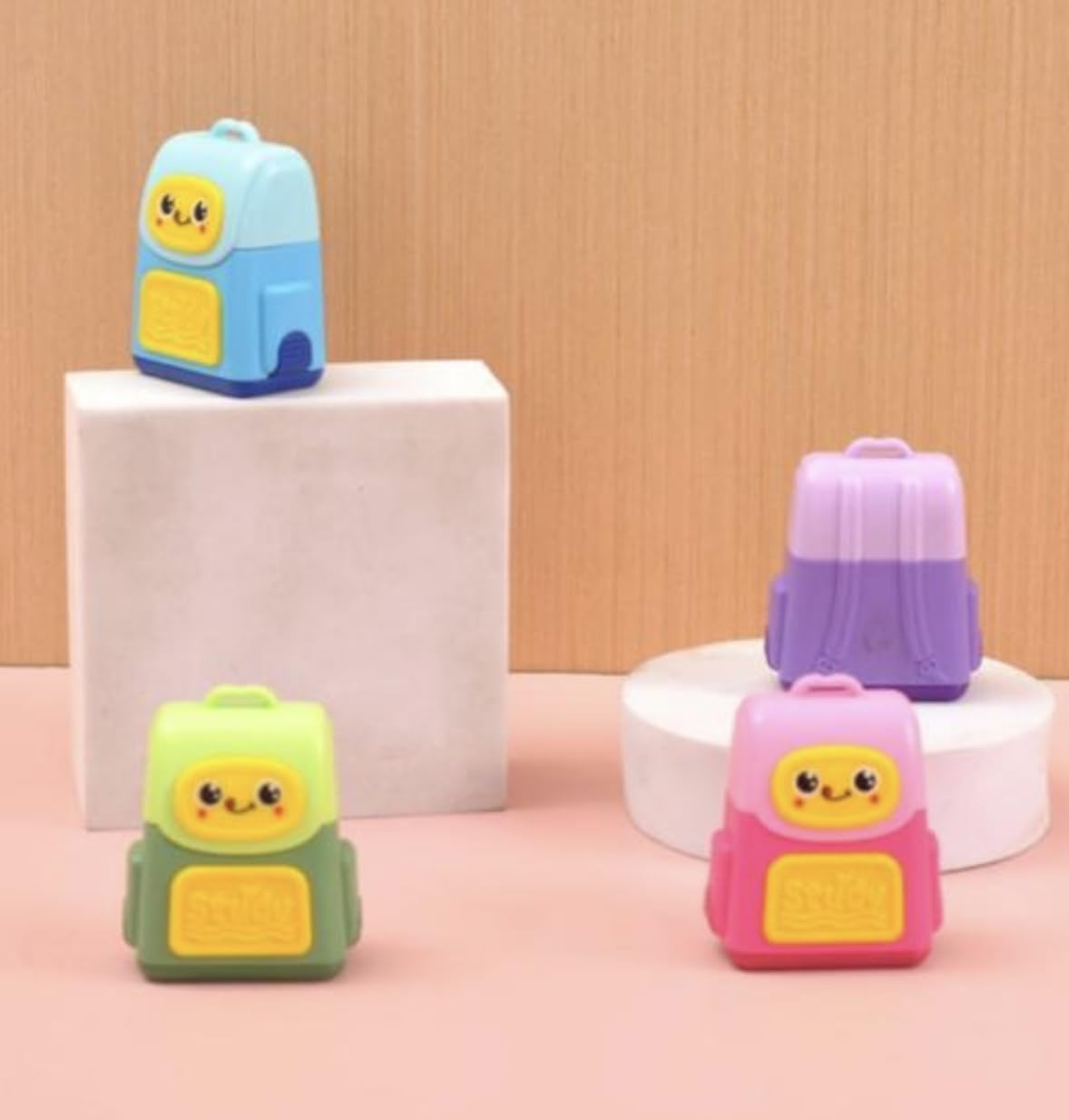 Four colorful backpack-shaped items on a pink and beige background