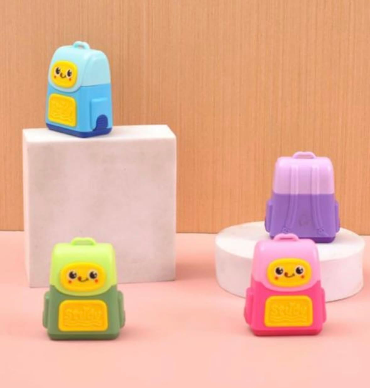 Four colorful backpack-shaped items on a pink and beige background