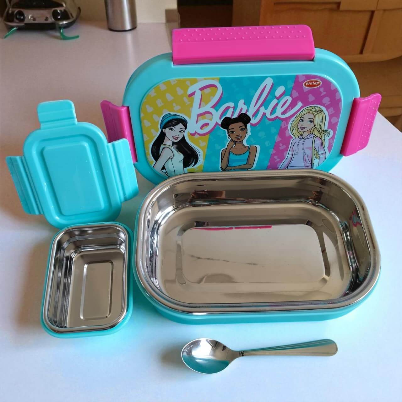 Barbie-themed lunch box set with containers and spoon on a kitchen counter
