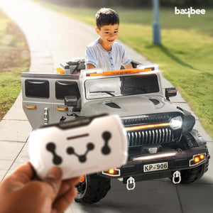 Grey and black battery operated kids jeep ride-on car with orange accents, features working headlights, overhead lights, and underbody glow, on rocky terrain." www.usmile.toys