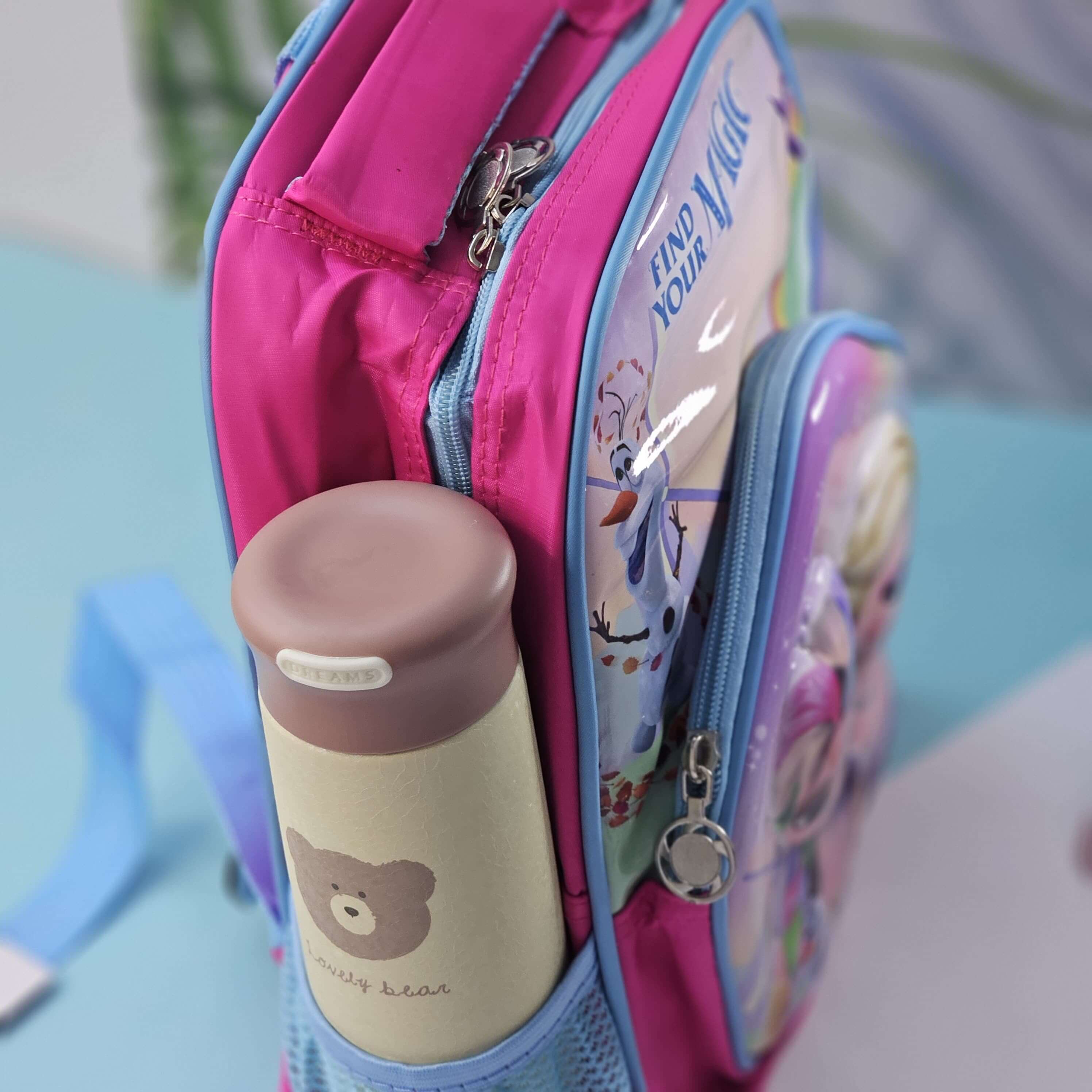 Pink backpack with a water bottle and cartoon design on a light blue surface