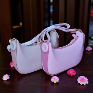 Two pink handbags on a wooden surface with small flowers around them.