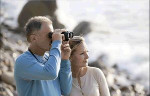 Man and woman using binoculars in a natural setting