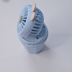 Front view of two Usmile Toys Hi Speed Kids Desk Fans, a blue and a pink one, showing their round grilles with a 'hello' emoji and charming bunny ears, suitable for adding a breeze and fun to any desk."