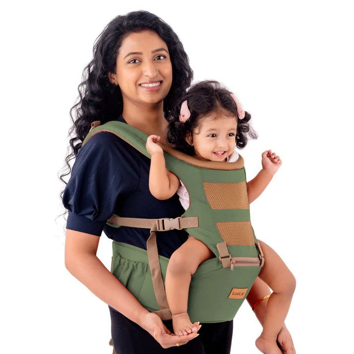 Smiling mother carrying a happy baby in a green Luvlap Royal Hip Seat Baby Carrier, designed for ergonomic comfort and support for both parent and child. Shows the baby facing forward. From uSmile.toys." www.usmile.toys 