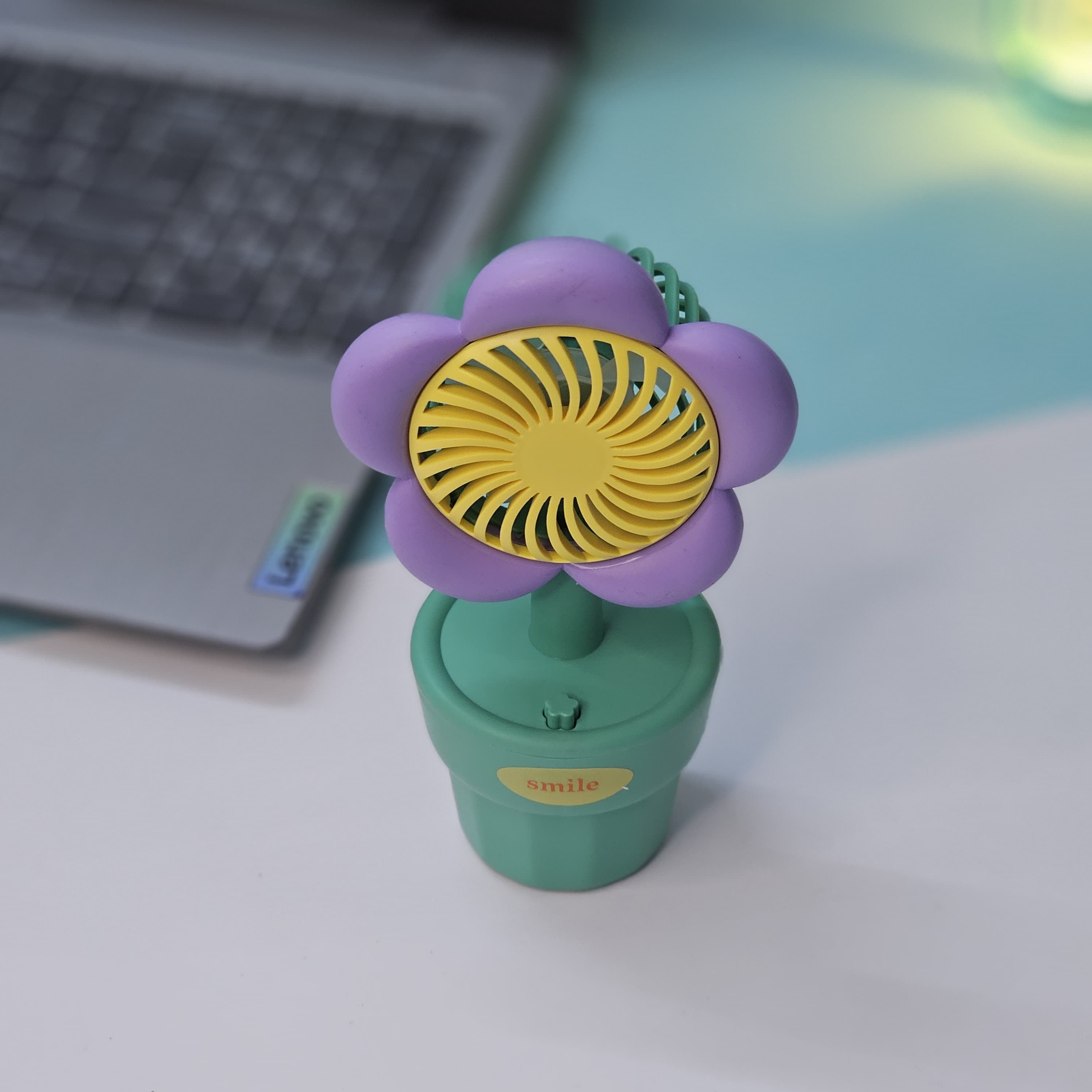 Usmile Toys 'Mini Desk Fan for Kids': an adorable flower-designed fan in yellow, purple, and pink, providing a gentle breeze as a cute desktop accessory."www.usmile.toys