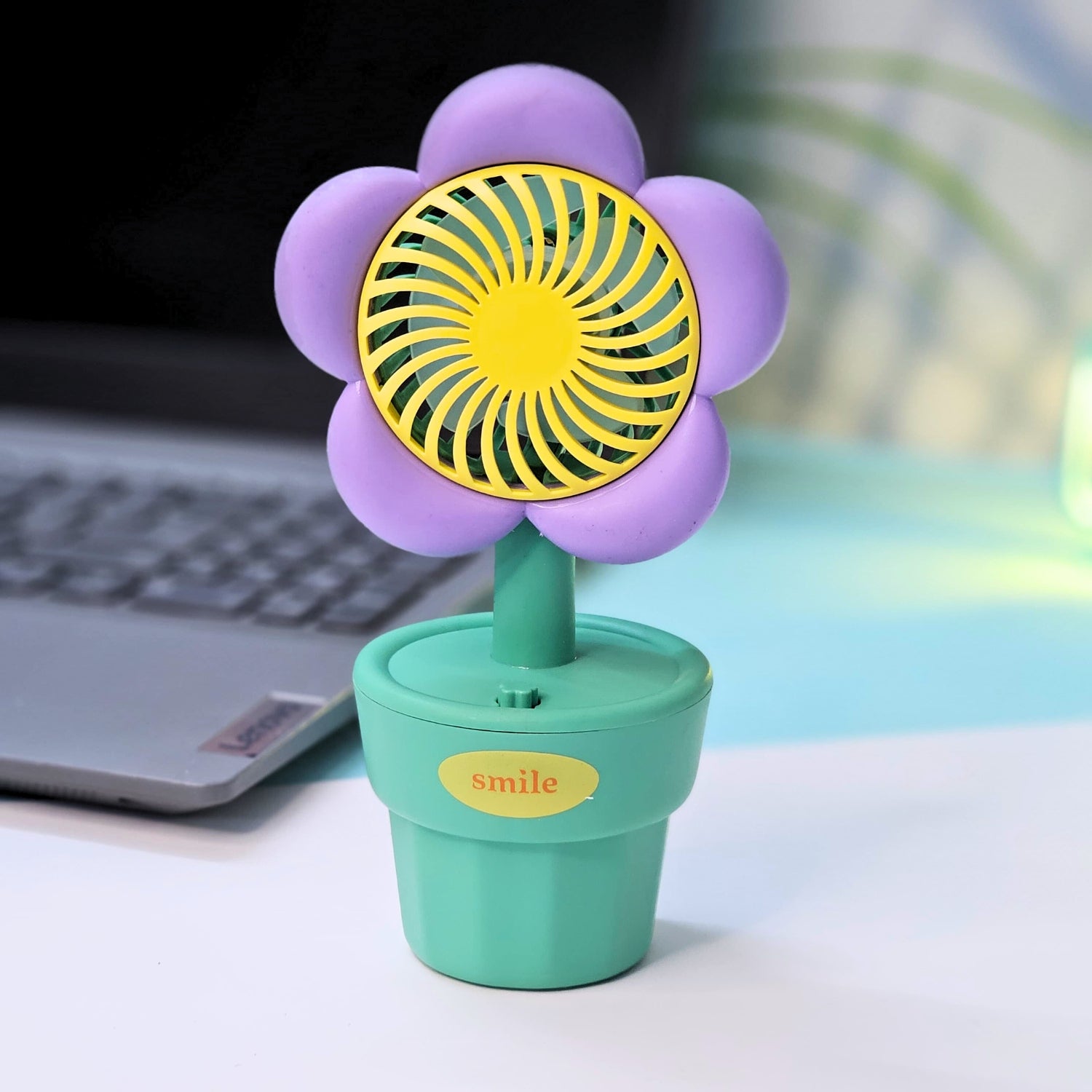 Usmile Toys 'Mini Desk Fan for Kids': an adorable flower-designed fan in yellow, purple, and pink, providing a gentle breeze as a cute desktop accessory.