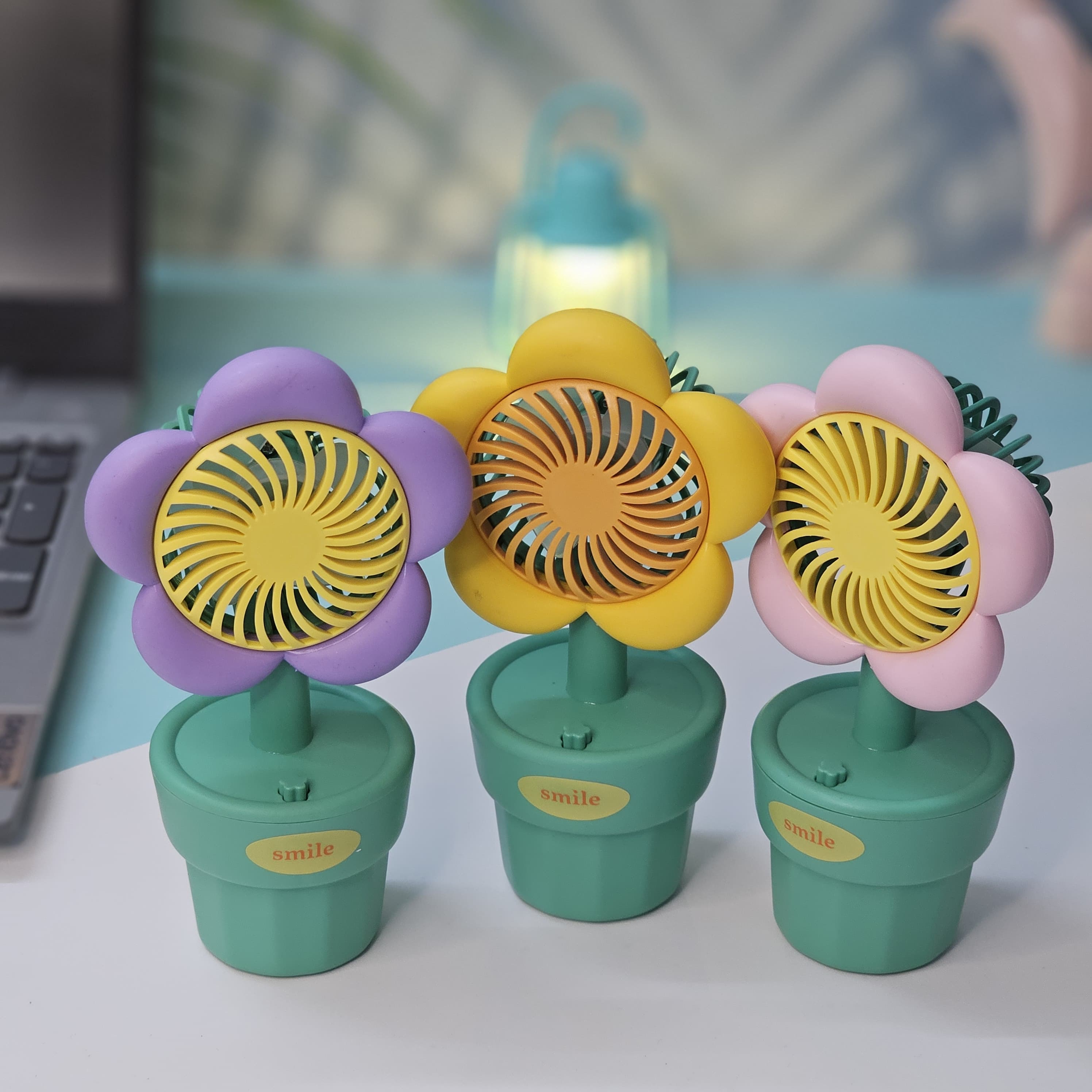 Usmile Toys 'Mini Desk Fan for Kids': an adorable flower-designed fan in yellow, purple, and pink, providing a gentle breeze as a cute desktop accessory."www.usmile.toys