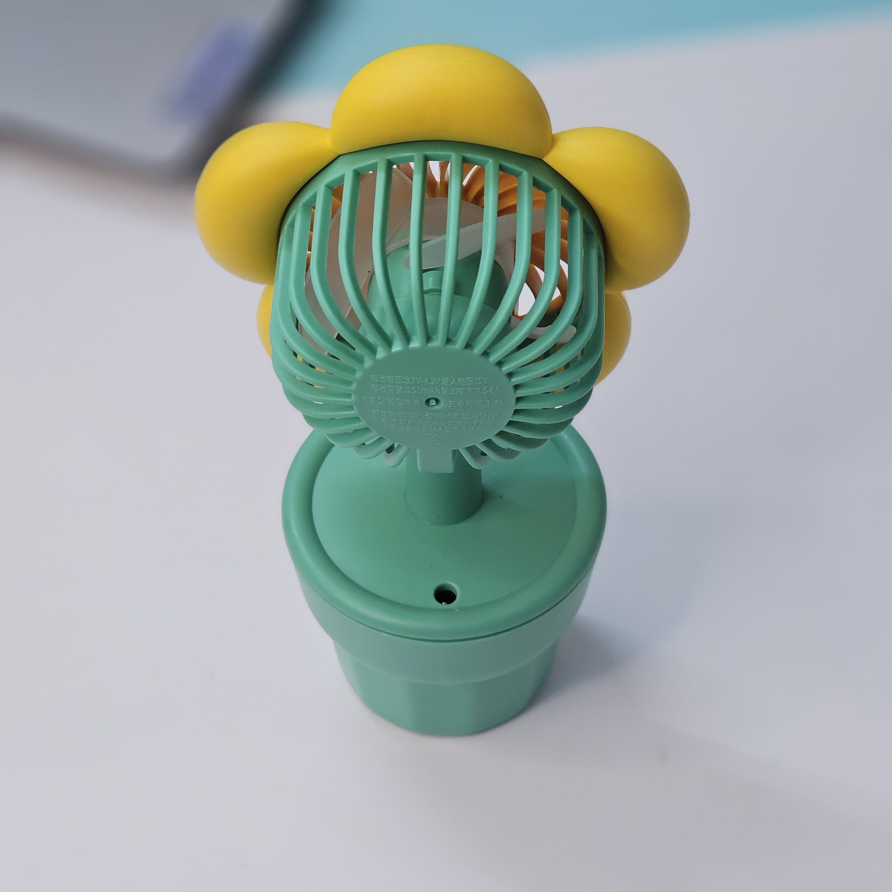 Front view of three Usmile Toys flower-shaped portable fans, featuring colorful petals and a 'smile' engraved green pot base, ideal for children. www.usmile.toys