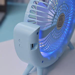 Close-up of a Usmile Toys unique desk fan, showing its light blue curved design, fan blades, and the soft blue illumination from its integrated LED lights." www.usmile.toys