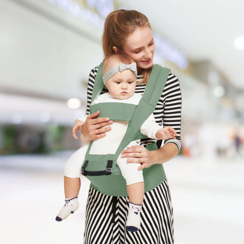 Happy mother carrying her baby in a green R For Rabbit Upsy Daisy 4-in-1 Baby Carrier with ergonomic design, suitable for multiple carrying positions. Shows a baby facing outwards, securely strapped. From uSmile.toys." www.usmile.toys