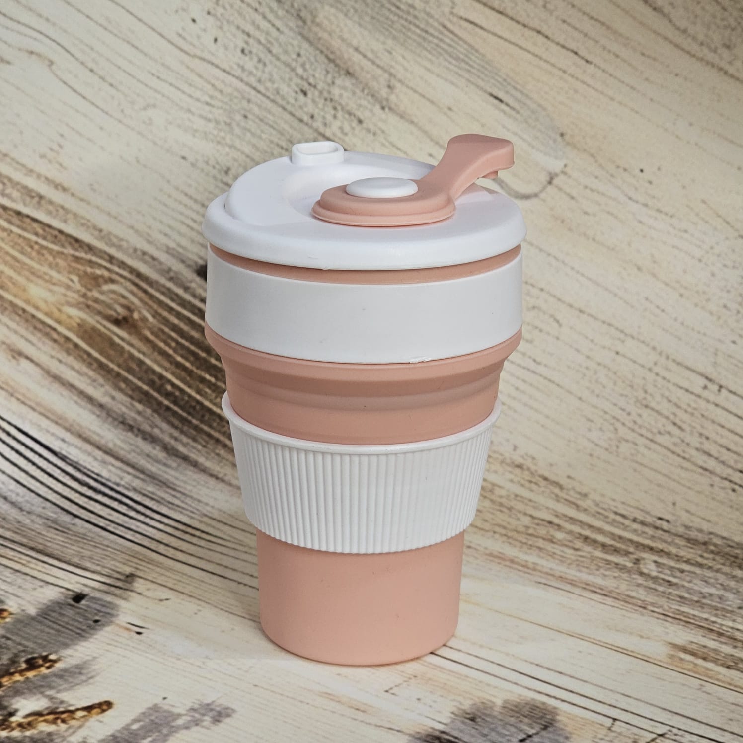 Pink and white 300ml pocket-size silicone travel coffee cup with a ridged grip and attached drinking spout cover. www.usmile.toys