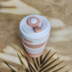 Pink and white 300ml pocket-size silicone travel coffee cup with a ridged grip and attached drinking spout cover. www.usmile.toys