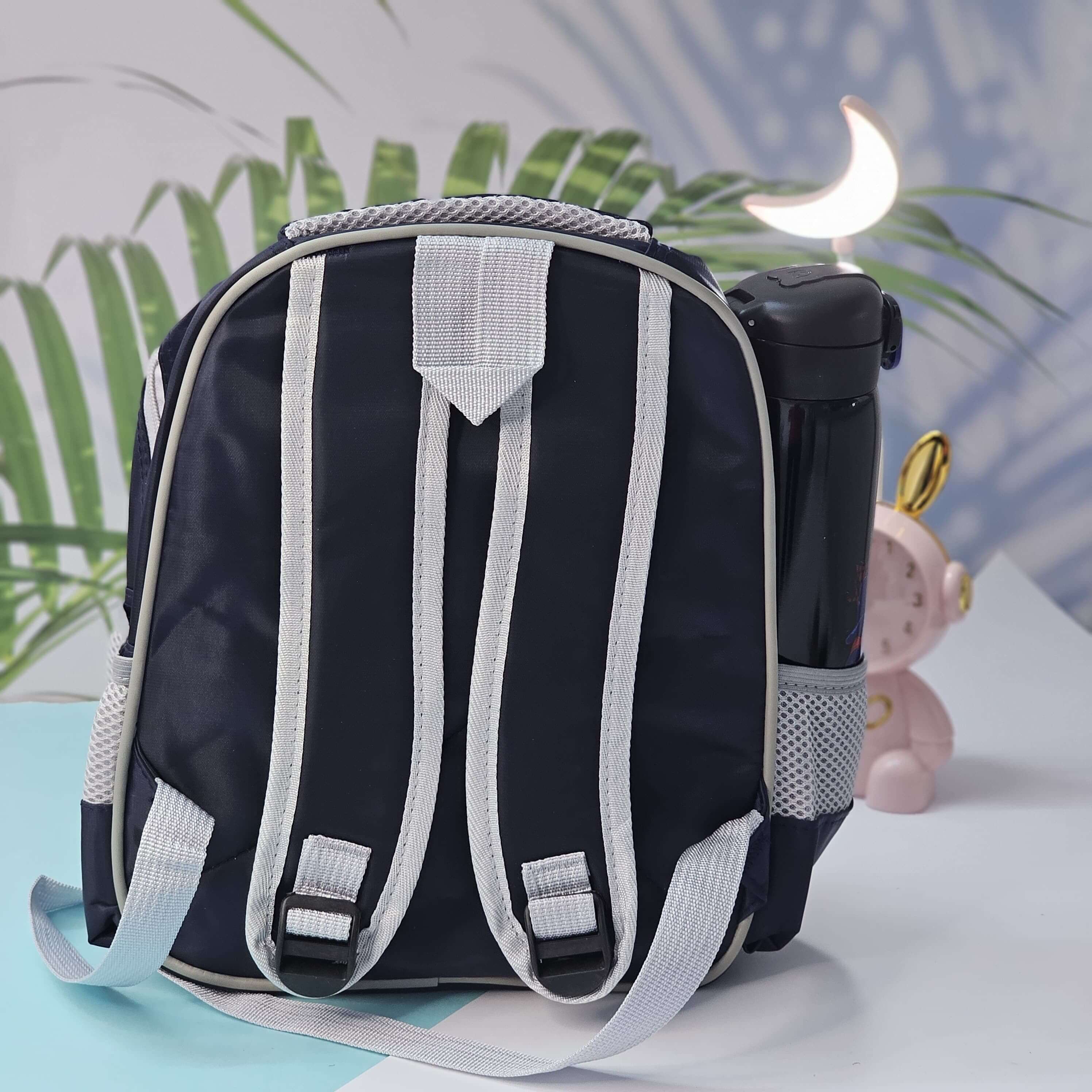 Black and white backpack on a light blue surface with a blurred green plant background