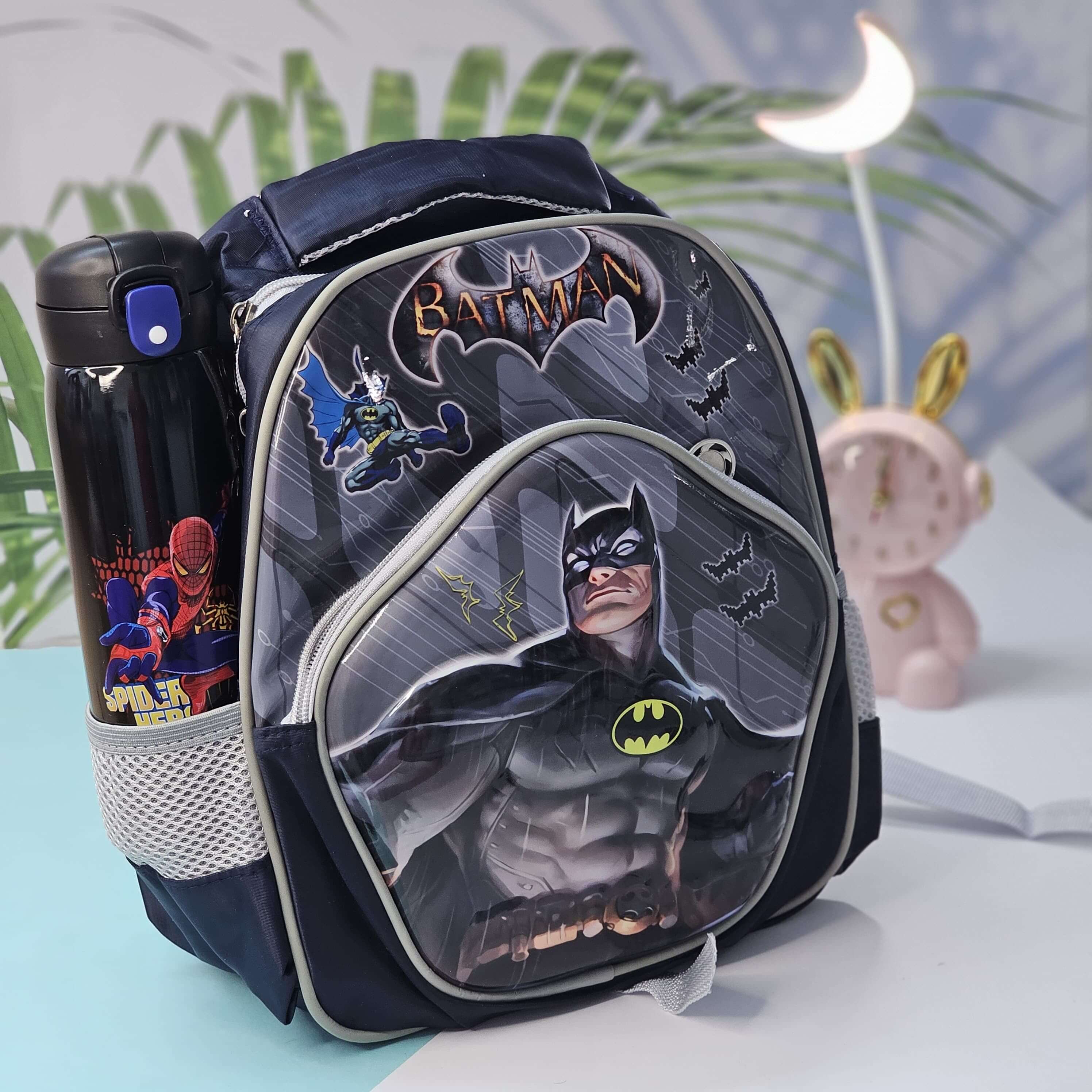 Batman-themed backpack with water bottle on a light blue surface