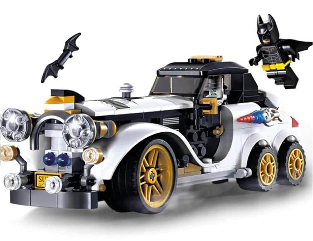 Lego-style building block set featuring a white classic car with gold wheels, Batman minifigure flying above, and Batarang accessory. Perfect for kids to assemble superhero adventures. www.usmile.toys