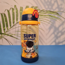 600ml astronaut-themed water bottle for kids featuring a leak-proof design and one-touch flip-open lid. The bottle has a transparent body with space and cartoon graphics, including the word 'SUPER' and an astronaut illustration. The cap is shown in a close-up inset, highlighting the one-key button for opening. The bottle is partially submerged in splashing water, emphasizing its leakproof and durable quality. Available in random colors, ideal for school or travel use