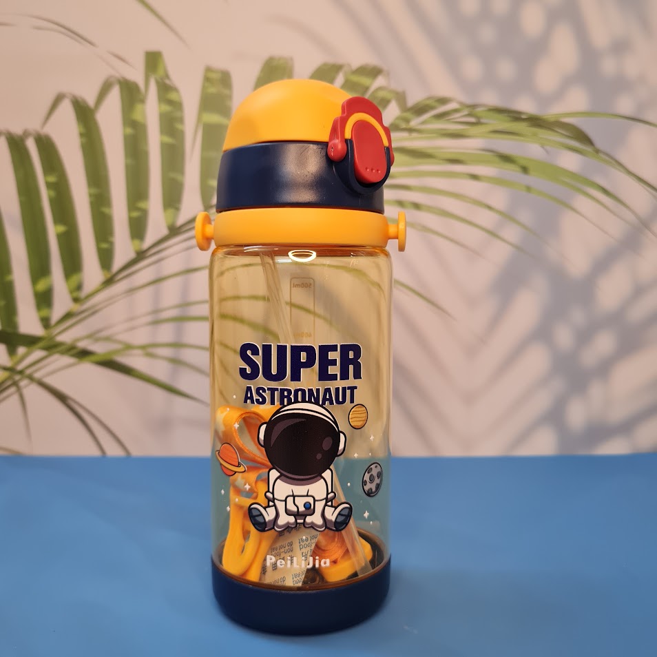 600ml astronaut-themed water bottle for kids featuring a leak-proof design and one-touch flip-open lid. The bottle has a transparent body with space and cartoon graphics, including the word 'SUPER' and an astronaut illustration. The cap is shown in a close-up inset, highlighting the one-key button for opening. The bottle is partially submerged in splashing water, emphasizing its leakproof and durable quality. Available in random colors, ideal for school or travel use