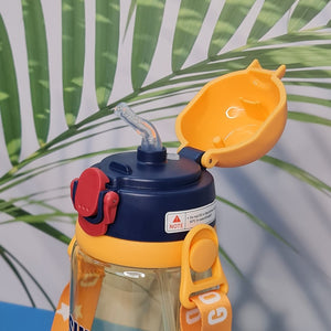 600ml astronaut-themed water bottle for kids featuring a leak-proof design and one-touch flip-open lid. The bottle has a transparent body with space and cartoon graphics, including the word 'SUPER' and an astronaut illustration. The cap is shown in a close-up inset, highlighting the one-key button for opening. The bottle is partially submerged in splashing water, emphasizing its leakproof and durable quality. Available in random colors, ideal for school or travel use