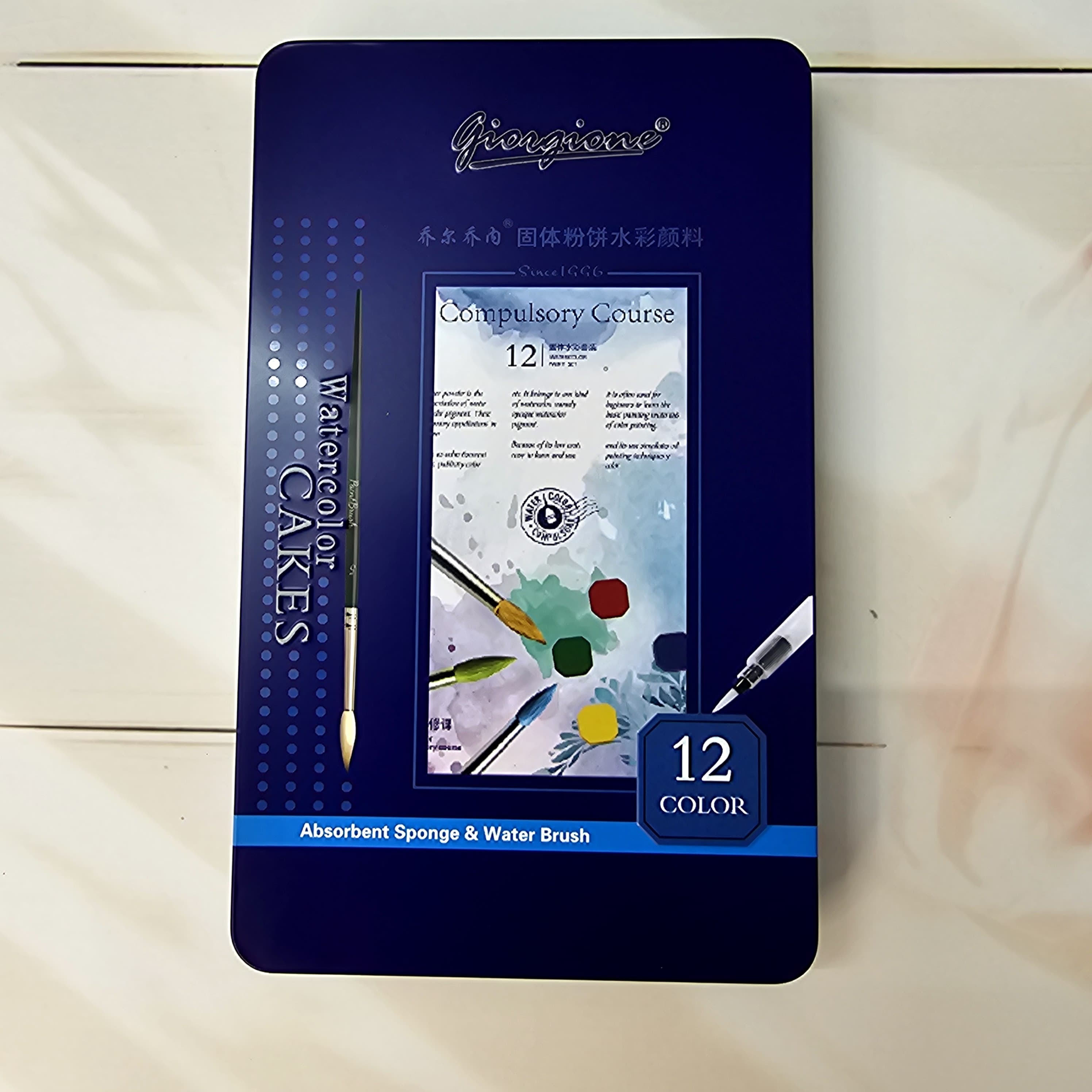 Dark blue box for a 12-color Giorgione Watercolor Cakes set by Usmile Toys, including an absorbent sponge and water brush, an ideal art kit for children." www.usmile.toys