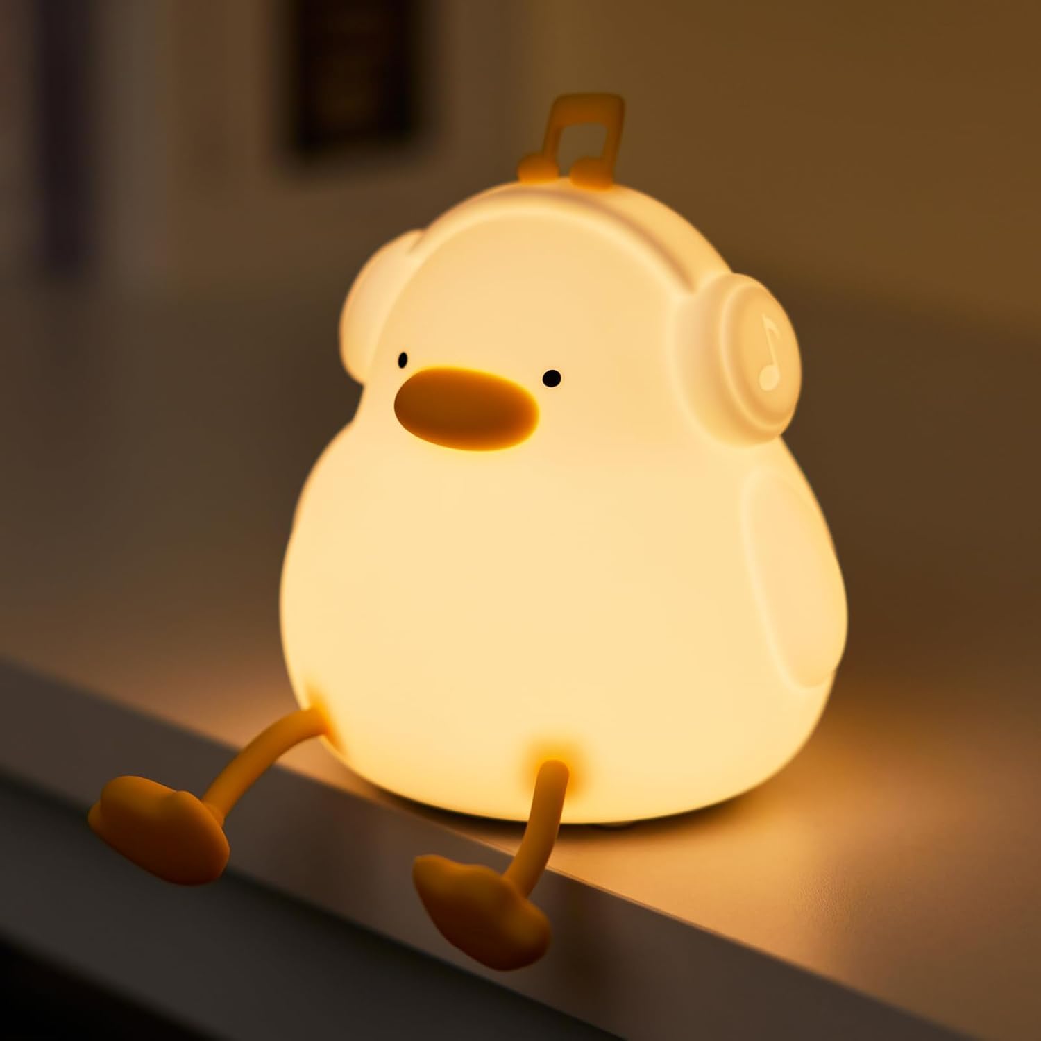 Adorable glowing white silicone night lamp for kids, shaped like a sitting duck wearing headphones with a music note accent. Provides a soft, comforting light. From uSmile.toys. www.usmile.toys