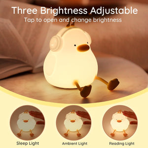 Adorable glowing white silicone night lamp for kids, shaped like a sitting duck wearing headphones with a music note accent. Provides a soft, comforting light. From uSmile.toys. www.usmile.toys