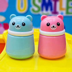 Adorable pink bear powder puff container with a smiling face and small ears, accompanied by a light blue bear case in the background, ideal for child care and personal hygiene from Usmile Toys. www.usmile.toys