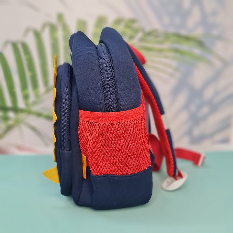 Small, navy blue backpack designed for children, featuring a red dinosaur applique with yellow spikes and white teeth on the front pocket. Above the dinosaur is embroidered red cursive text that reads "My Funny Dino". The backpack has red mesh side pockets and black zipper pulls