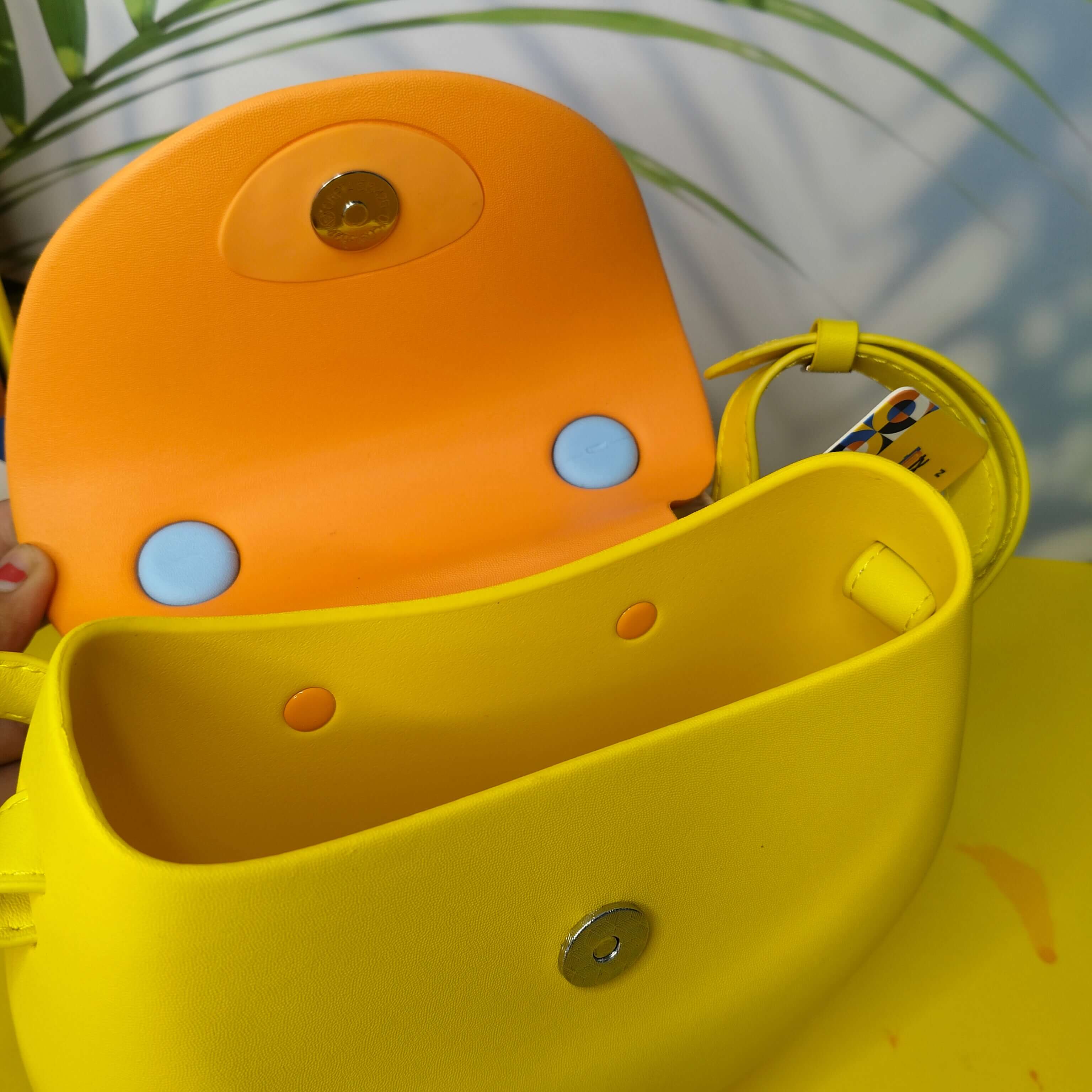 Close-up of a yellow and orange children's chair with blue buttons against a blurred natural background.