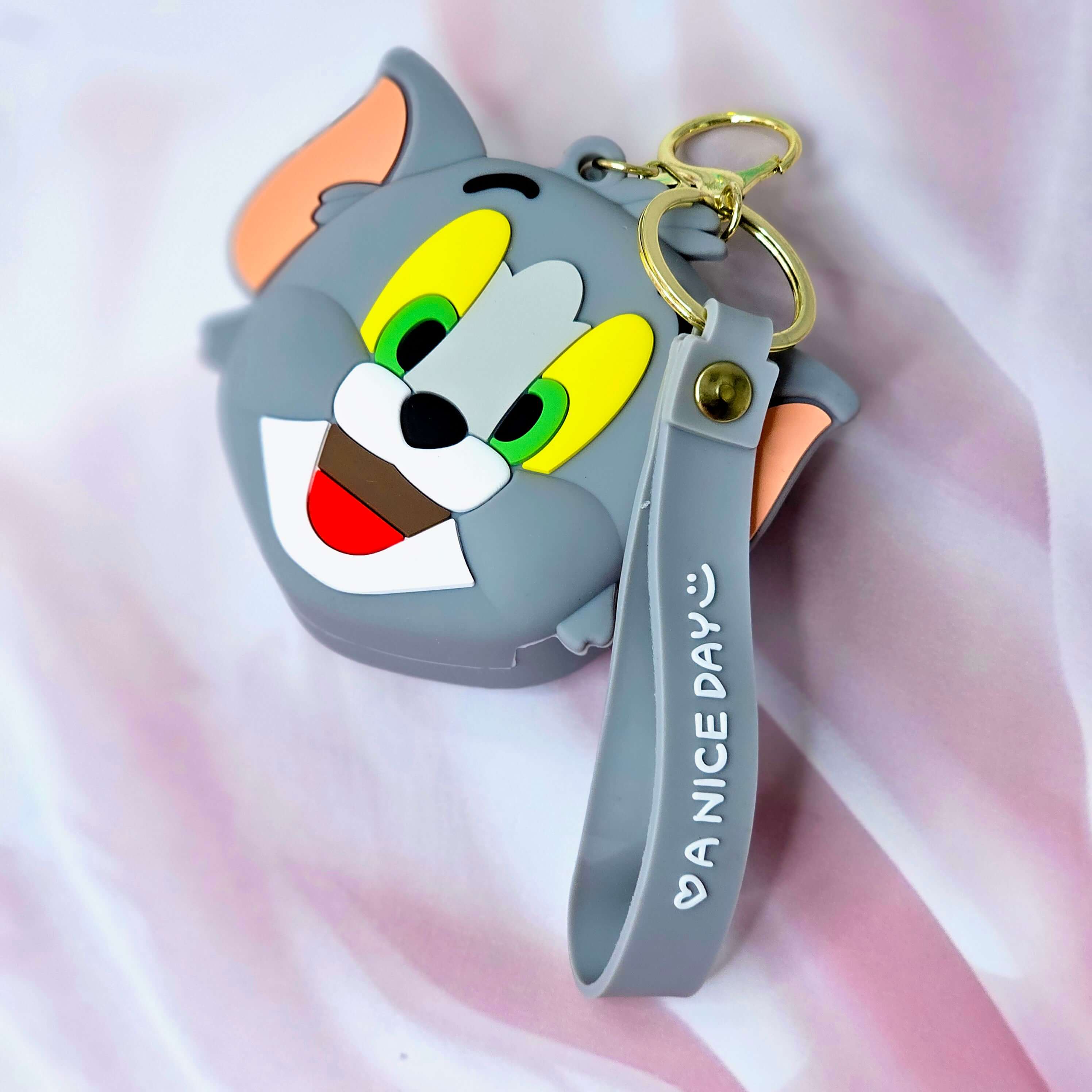 Cute Tom cartoon character silicone coin purse and keychain, featuring green eyes, a wide smile, and a grey wrist strap with "A NICE DAY :)" text. This fun and practical accessory is perfect for kids and fans of cartoon characters, ideal for holding coins or small items. www.usmile.com