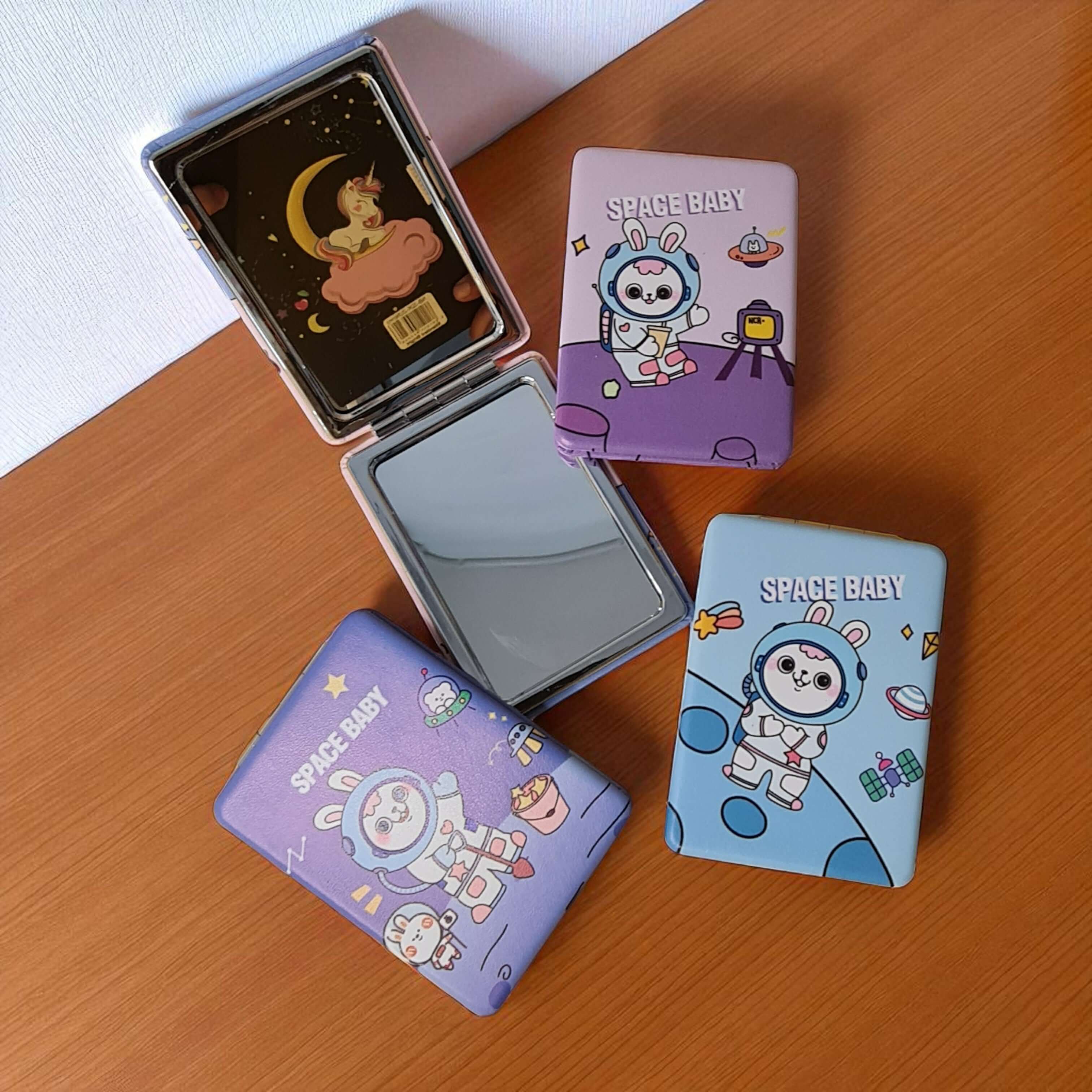 Compact mirrors with cartoon designs on a wooden surface