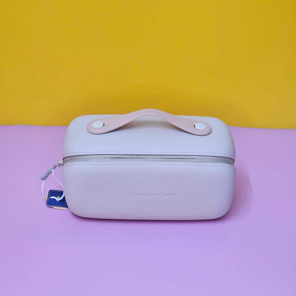 Light pink travel case with handle on a purple surface against a yellow background
