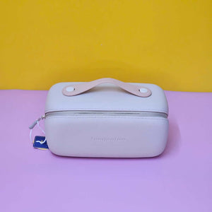 Light pink travel case with handle on a purple surface against a yellow background