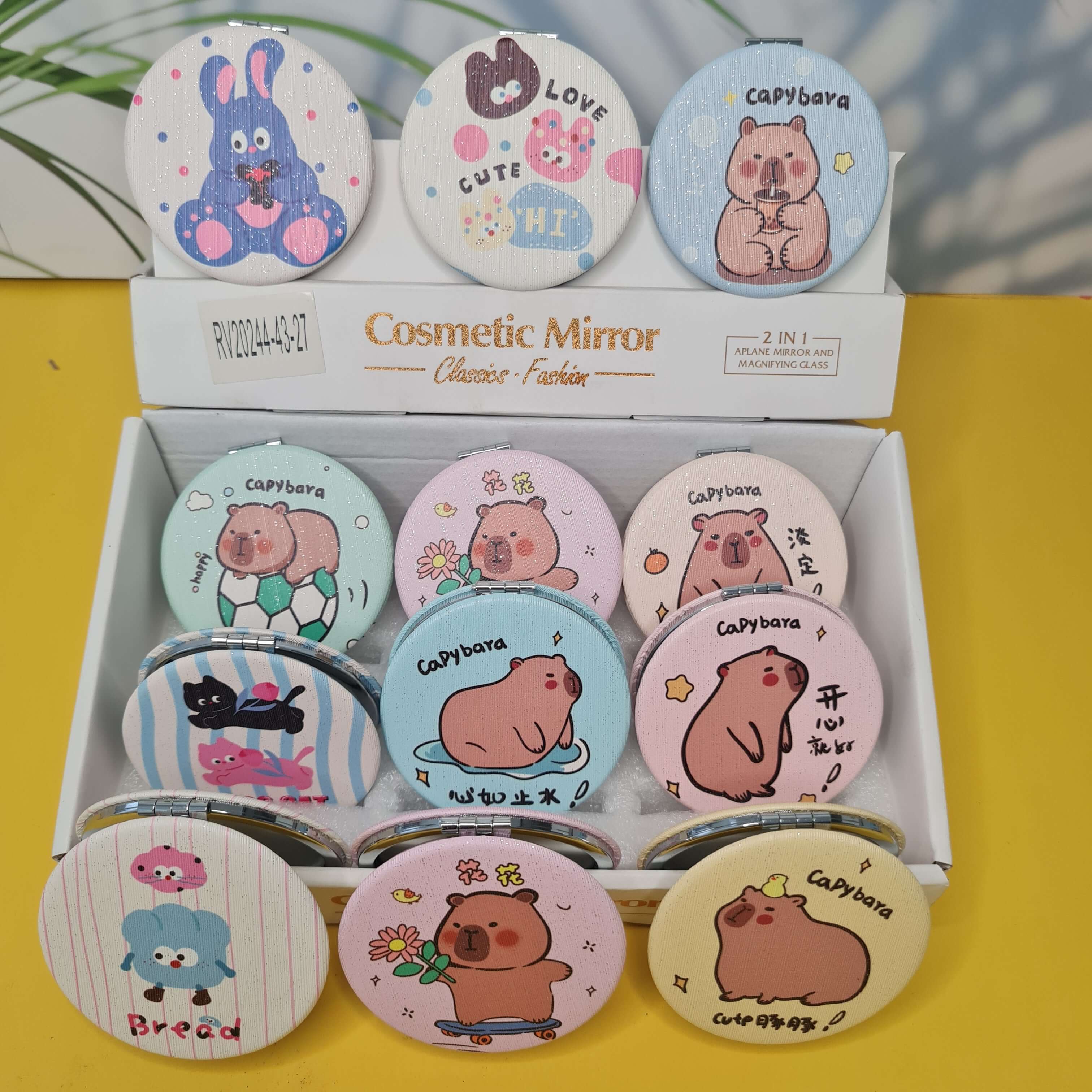 Set of cartoon-themed cosmetic mirrors in a box on a yellow background