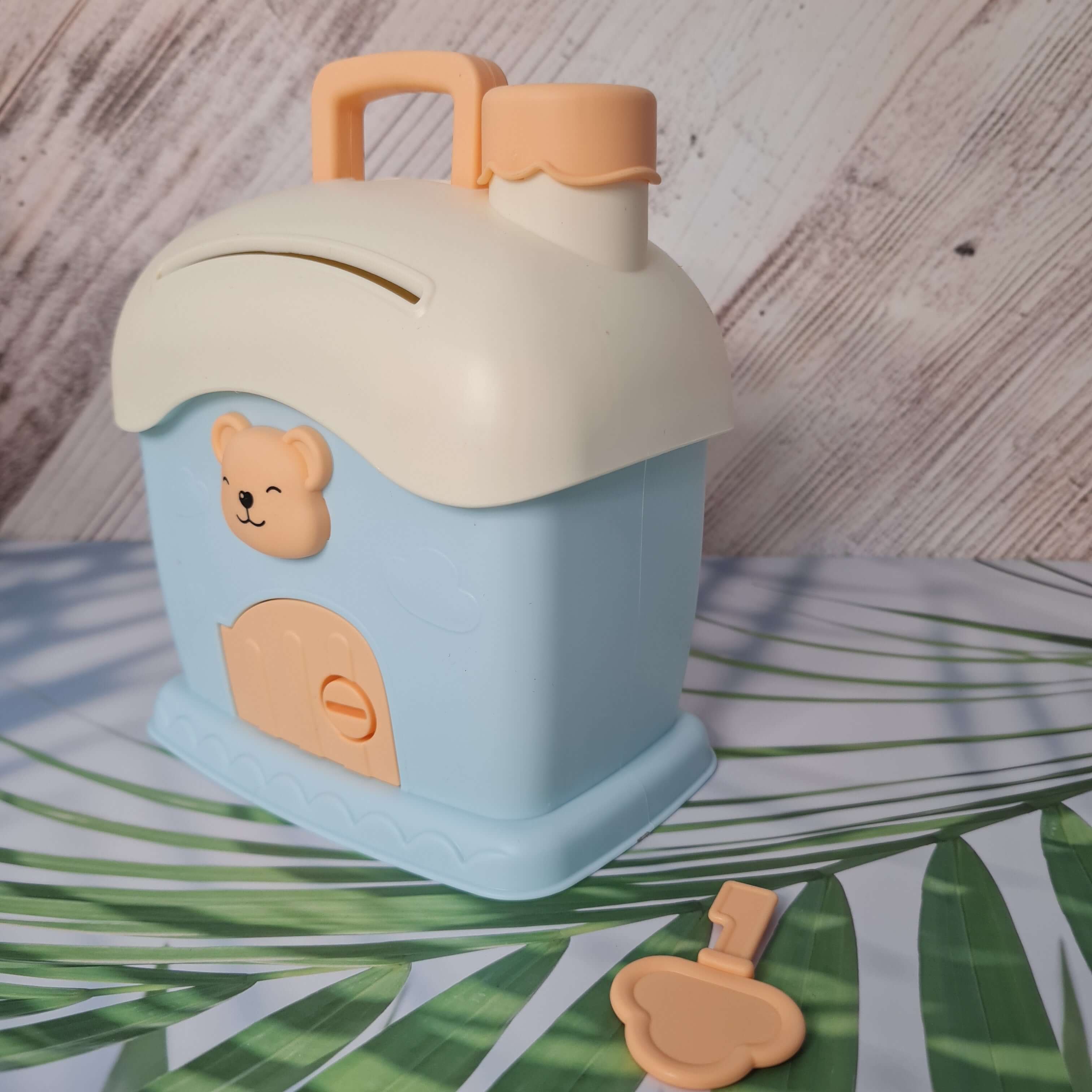 Children's lunch box with bear design on a wooden surface with green leaves in the background