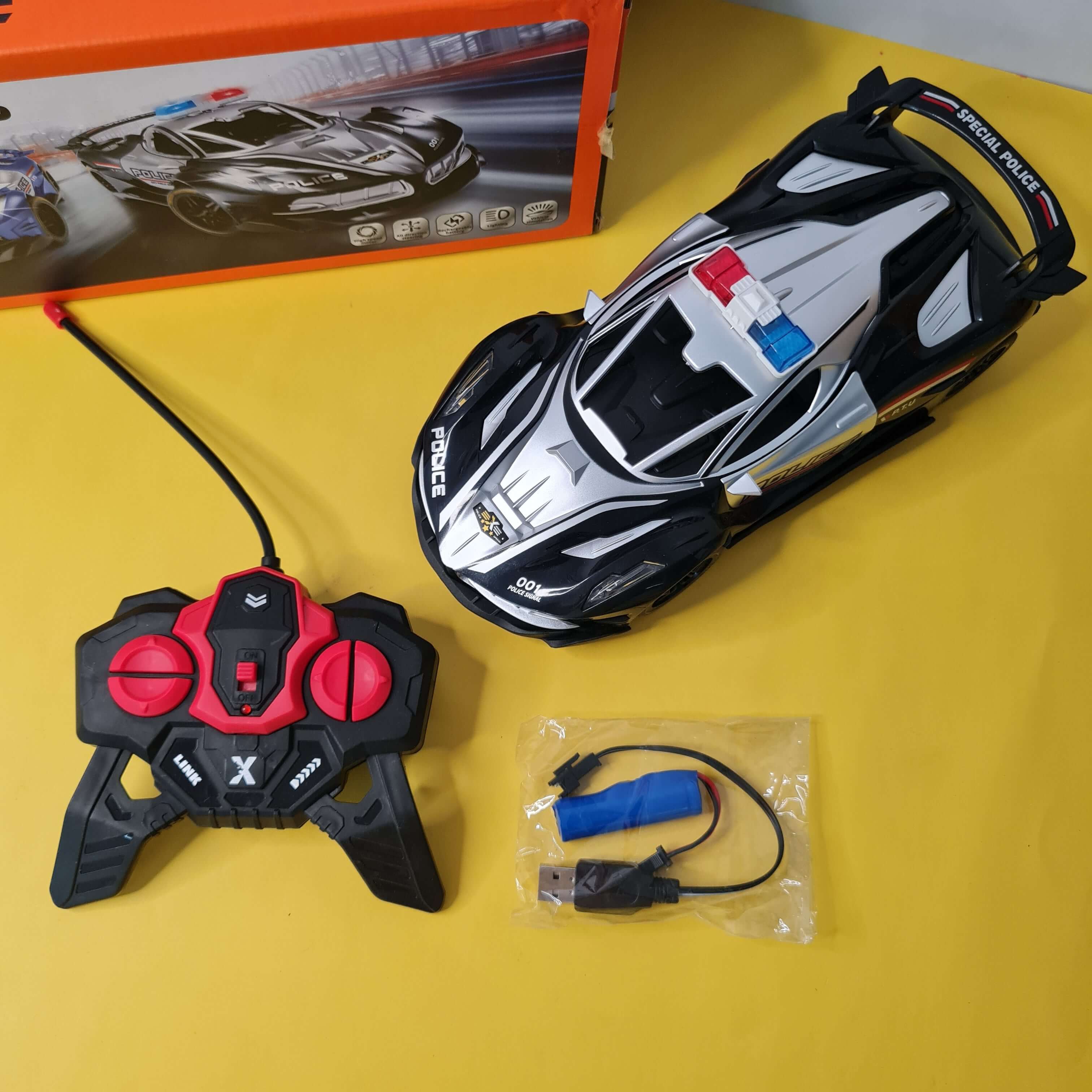 Toy police car with remote control and accessories on a yellow surface