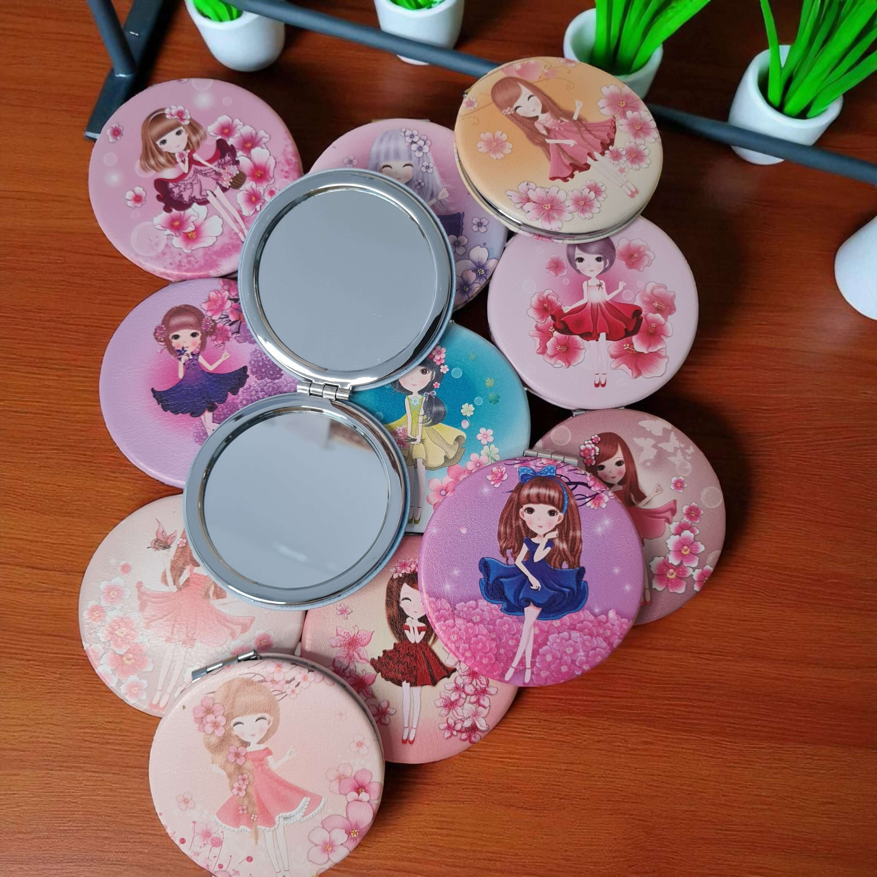 Compact mirrors with cartoon character designs on a wooden surface