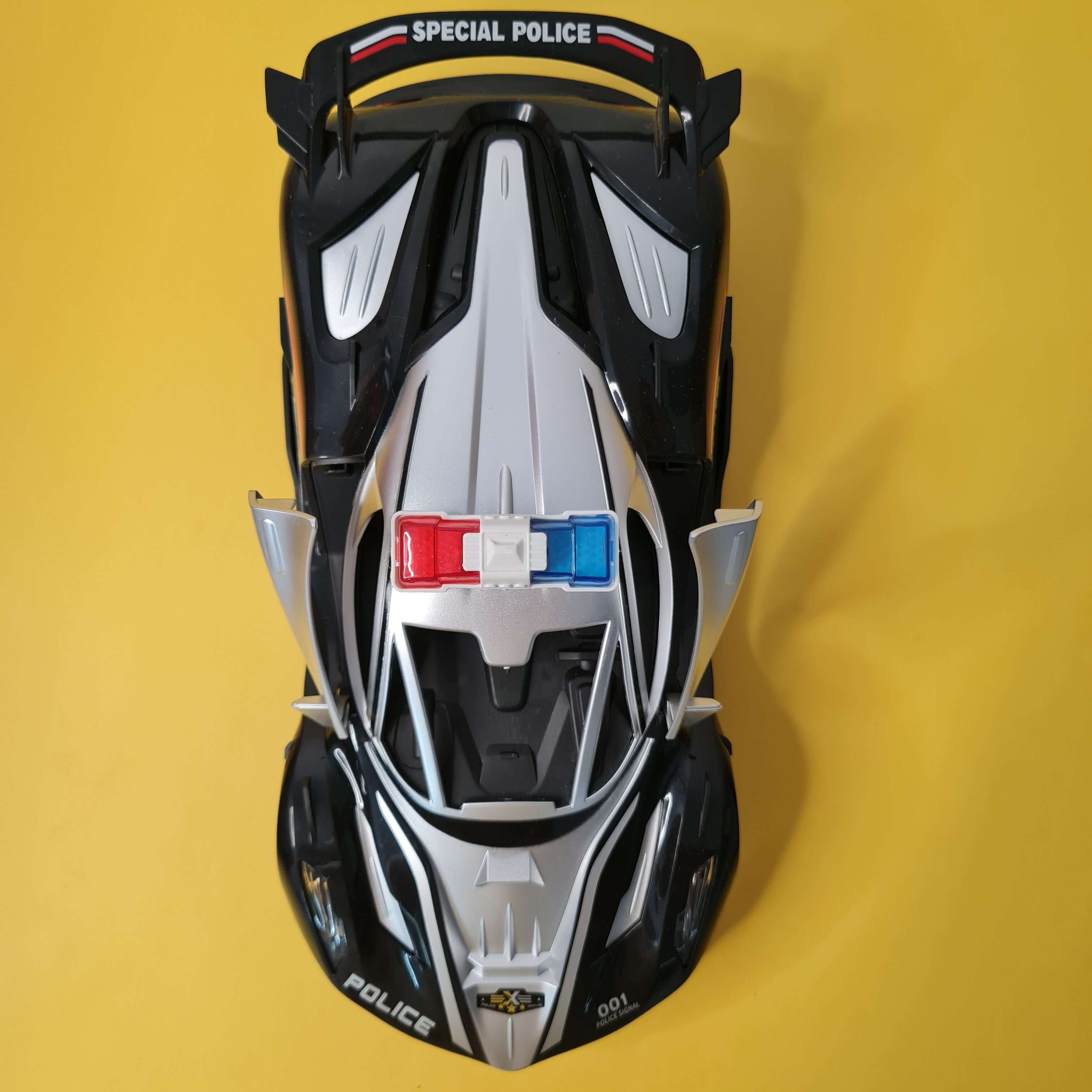 Top-down view of a toy police car on a yellow background