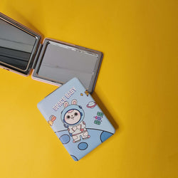 Compact mirror with cartoon design on a yellow background