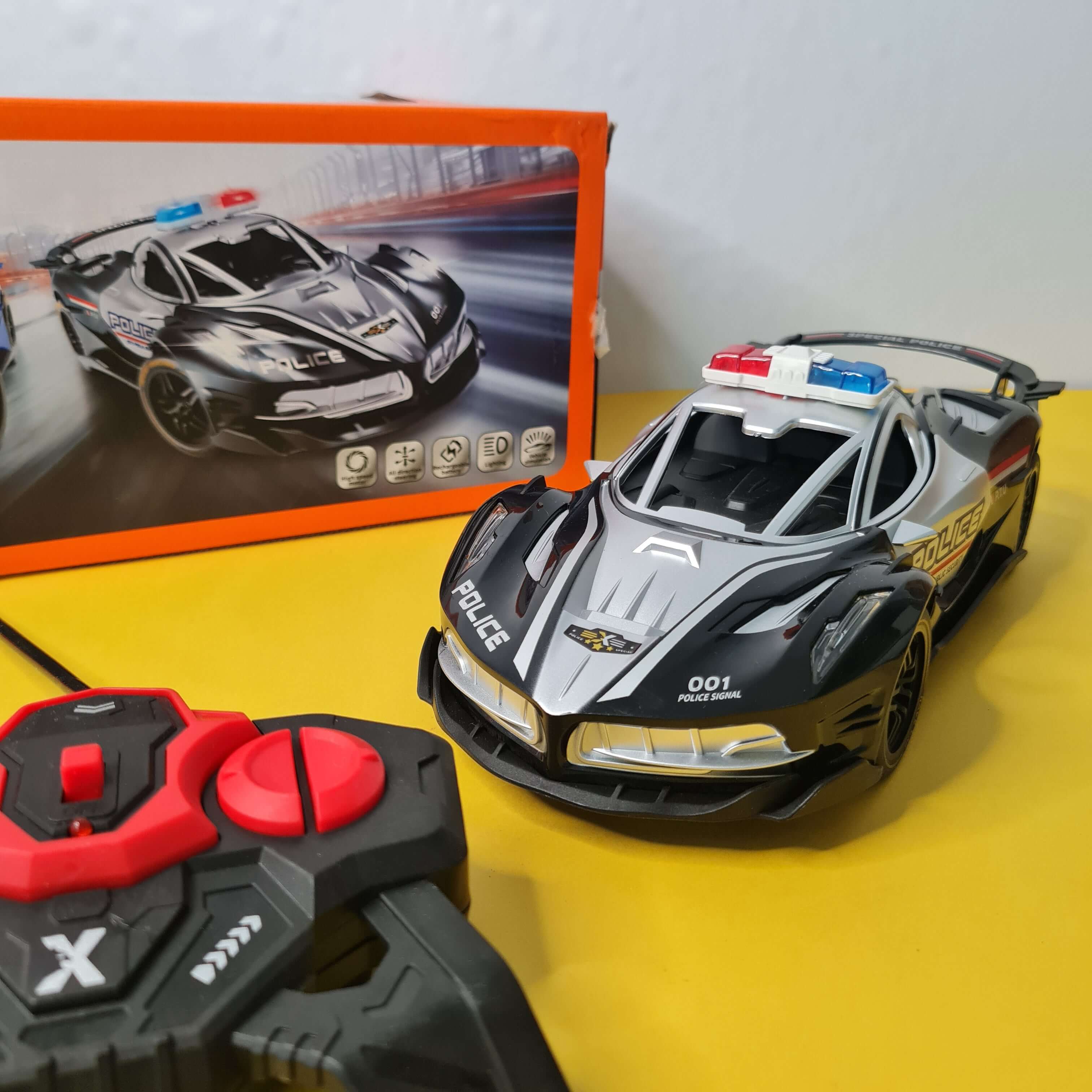Black and gray police helmet with red accents on a yellow surface, next to a box with similar design.