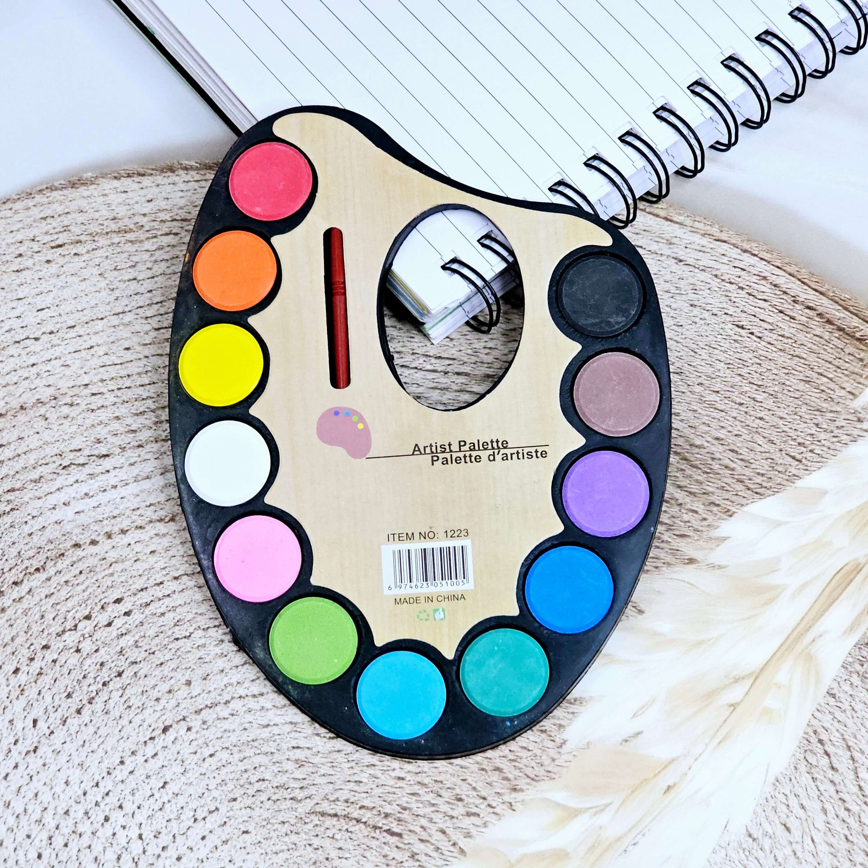 Wooden artist palette watercolor set with 12 vibrant colors and a small brush, ideal for kids' art and painting projects, shown on a textured mat by Usmile Toys.www.usmile.toys