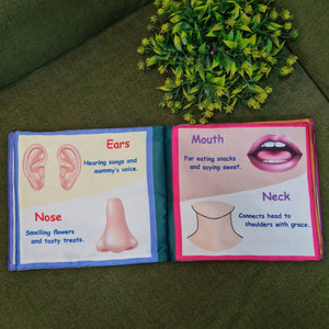 A "My Amazing Body: Head to Toe" fabric book by Kidogen, showing a cartoon child meditating with illustrations of body parts and organs around them.