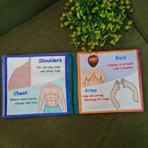 A "My Amazing Body: Head to Toe" fabric book by Kidogen, showing a cartoon child meditating with illustrations of body parts and organs around them.