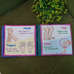 A "My Amazing Body: Head to Toe" fabric book by Kidogen, showing a cartoon child meditating with illustrations of body parts and organs around them.