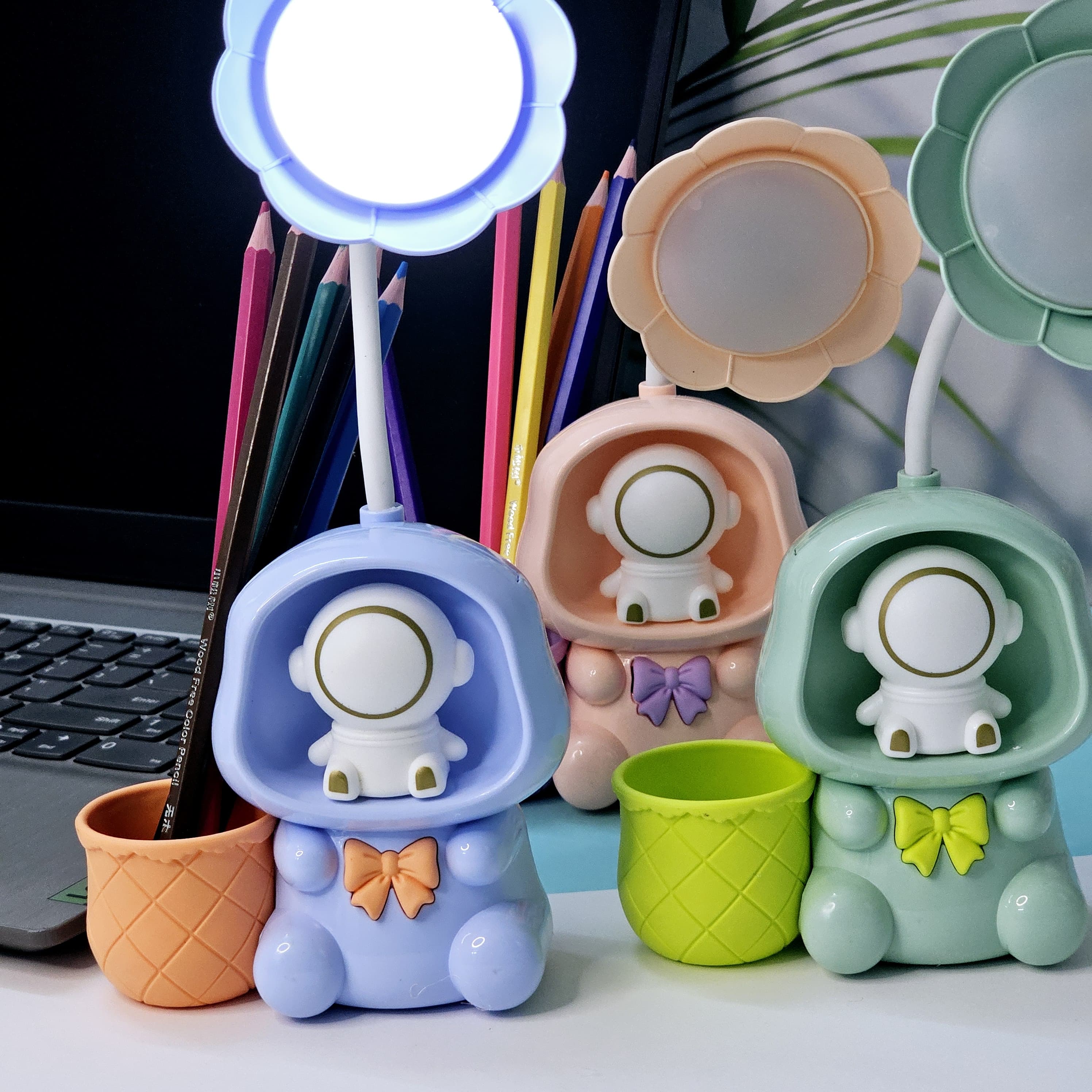 "Usmile Toys multifunctional kids' lamp: a blue, pink, and green astronaut figure with a flower-petal light and an integrated pencil holder, enhancing study time and room decor." www.usmile.toys