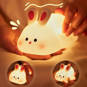 "Adorable glowing white silicone night lamp for kids, shaped like a cute rabbit with big ears and a cheerful face, being gently held. Provides a soft, comforting light for bedrooms from uSmile.toys." www.usmile.toys
