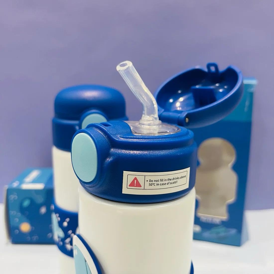 White stainless steel insulated water bottle for kids with a blue cap and a wrap-around blue band featuring an astronaut and space designs. 500 ML capacity. Ideal for hot or cold beverages for school and travel from uSmile.toys." www.usmile.toys