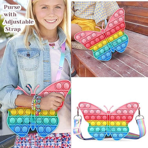 Front view of a Usmile Toys girls' crossbody purse, shaped like a rainbow butterfly Pop It fidget toy, with a striped strap and accompanying accessories." www.usmile.toys