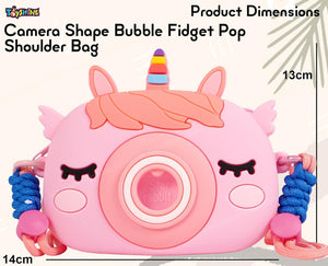 Front view of a 'Kawaii-G' camera-shaped silicone bag for children, in pink with a rainbow unicorn horn, alongside a pink unicorn comb, 'Fruit' keychain, and unicorn keychains."