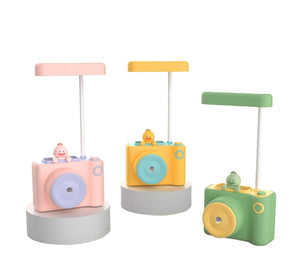Two cute camera-shaped study desk LED lamps for kids, one peach and one light blue, each featuring a pencil holder and a built-in pencil sharpener. Ideal for reading and organizing stationery from uSmile.toys." www.usmile.toys